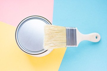 Paint metal round can and new brush on multi-colored background. Focus on brush. House renovation. Hobby.