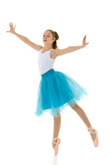 Fototapeta na wymiar Cute little girl in a tutu and pointe shoes dancing in the studi