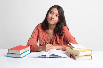 Young Asian woman read a book with books on table .