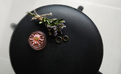 
wedding accessories: rings, a bouquet of flowers, women's perfumes on a glass table