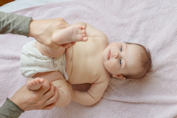 Top view of mother and her cute child on bed. Baby massage and exercises of gymnastics.