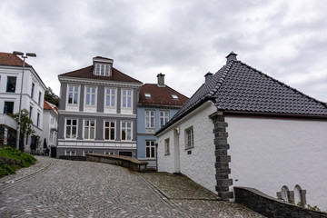 Fototapeta na wymiar Cozy traditional scandinavian architecture on cobblestoned streets in Bergen, Norway. Moody cityscape