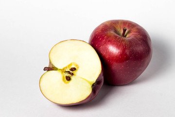Two apple on a white background. One apple is whole. the second apple is cut in half