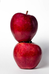 Two red apples on a white background. One apple lies on another apple
