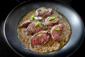 fresh cooking at home, venison meat from a chamois buck, roasted in a pan with herbs and young buds from a spruce tree