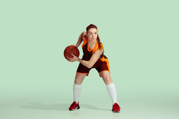 Young caucasian female basketball player in action, motion during gameplay isolated on mint colored...
