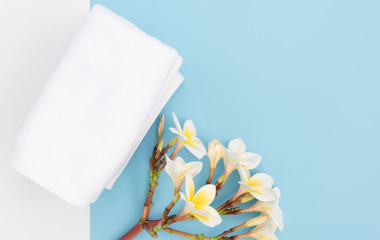 White towel and beautiful frangipal or plumeria spa flower on blue background,top view