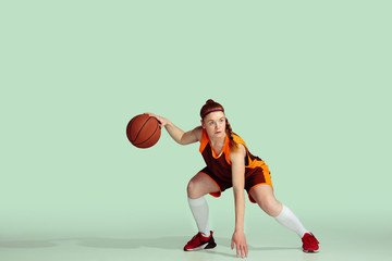 Young caucasian female basketball player in action, motion during gameplay isolated on mint colored...