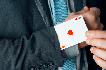Businessman in suit and tie show an ace up his sleeve