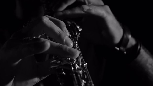 Musician playing flute on black background at night