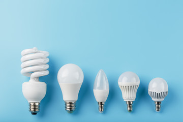 Energy-Saving light bulbs are arranged in a row on a blue background, top view.
