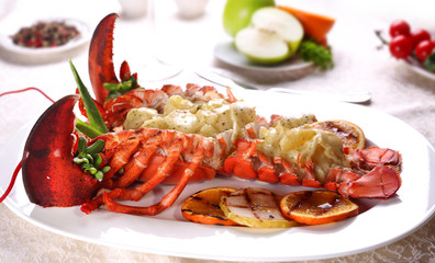 Baked lobster with applesauce and grilled bbq fruit on a white plate in a restaurant.