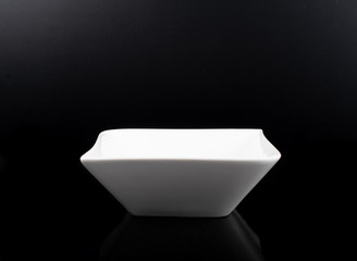 White porcelain bowl isolated in black, space for copy text. Simple, no food or other ingredients