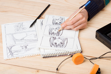 Artist drawing an anime comic book in a studio.