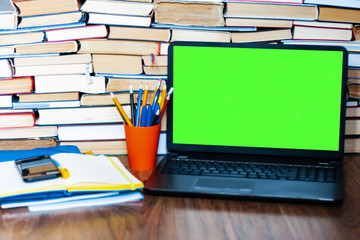 Textbook, notebook, green screen laptope and stack of books. Work from home, distance education background, stay home concept.
