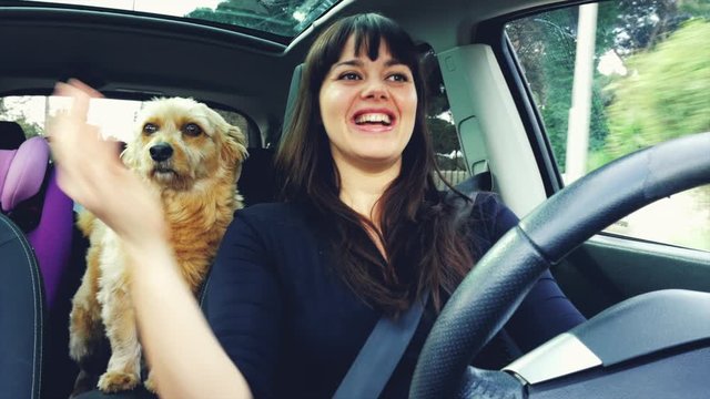 Woman with bangs cuddling dog driving car after end of quarantine coronavirus happy