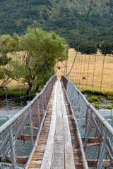 Obraz premium Suspension Bridge over the Matukituki River, along the Wanaka-Mount Aspiring Road, South Island, New Zealand