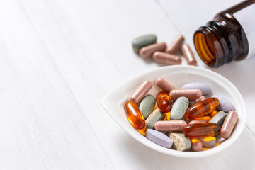 Variety of vitamin pills on white wooden background, supplemental and healthcare product