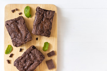 Top view of chocolate brownies on wooden board on white table, homemade sweet and dessert concept