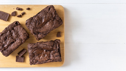 Top view of chocolate brownies on wooden board on white table, homemade sweet and dessert concept