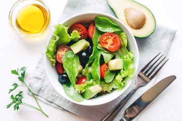 Fresh salad of avocado, cherry, arugula and olives made at home. Vegan food. The concept of healthy eating. Top view.
