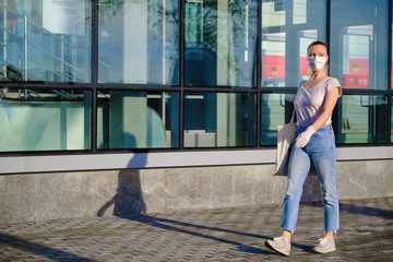 Naklejka premium European woman in protective mask and gloves walking outdoors during pandemic.