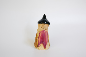Figure of a ceramic an old witch in a hat on the white background