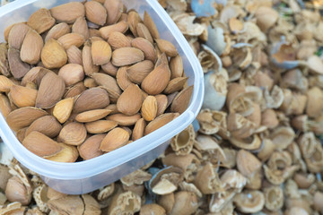 Peeled almonds in a transparent box. In the background, the shell is in blur.