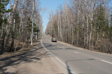 Two-lane car road in the spring forest going uphill.
