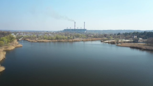 top view of a factory, farm, production. Environmental pollution, nature and river landscape, field and lake. industry, export, import. Plant set in beautiful sunny landscape