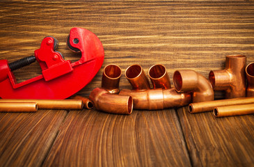 Red pipe cutter and copper pipes with connectors on vintage boards