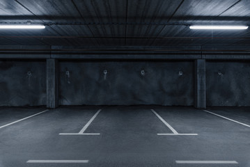 Sci fi looking dark and moody underground parking lot with fluorescent lights on.  Concrete wall - obrazy, fototapety, plakaty