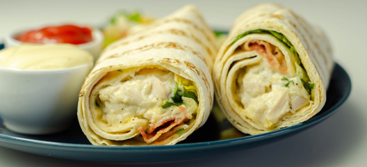 Tortilla wrap with chicken and beechwood smoked bacon served with mix salad on the blue plate