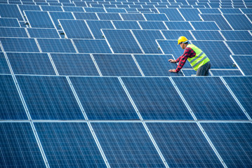 An Asian male worker is about to install solar panels. At the solar power generating station Asian workers take orders and install solar cells.