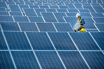 An Asian male worker is about to install solar panels. At the solar power generating station Asian workers take orders and install solar cells.