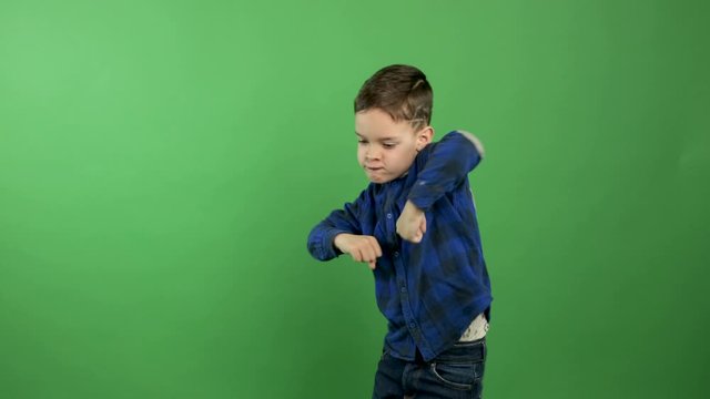 Home insulation covid-19. Cheerful kid boy dancing, children's disco on isolated green background. Classes indoors with children. Dancing parties help people get rid of nausea and anxiety
