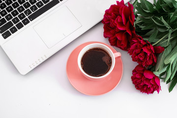 white laptop with black buttons and three red peonies and a cup of coffee
