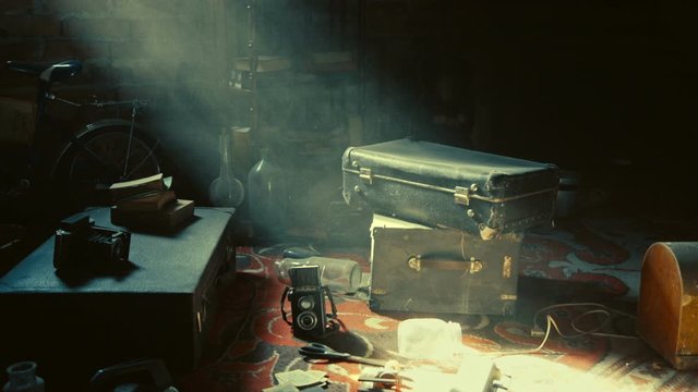 Old vintage stuff, suitcases, cameras, glass botles, rack with books, bicylce, and other objects are kept in the old mysterious attic - the place where magic things may happen, Zoom in, Slow motion.