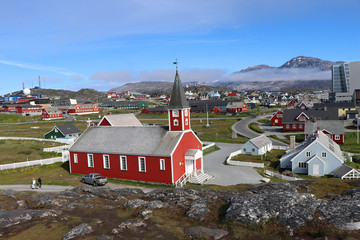 Nuuk Cathedral (Greenlandic: Annaassisitta Oqaluffia) or Church of Our Saviour and .colorful houses in Nuuk,the capital of Greenland, against the backdrop of mountains © Inna