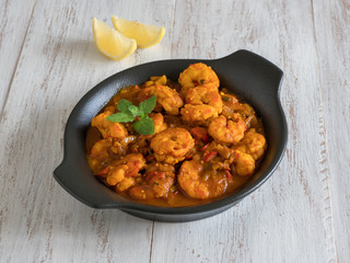 Prawns in curry sauce in a black pan close-up