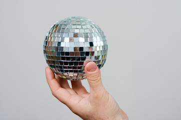 Close-up   hand of  a  man    holding  a  silver mirror  party  ball . Concept regarding parties...