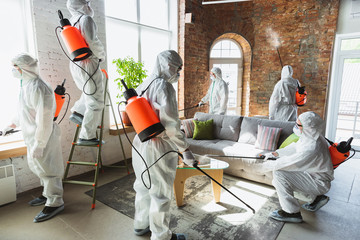 Coronavirus Pandemic. A disinfectors in a protective suit and mask sprays disinfectants in house or...