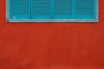 Closed blue shutters on a red wall.