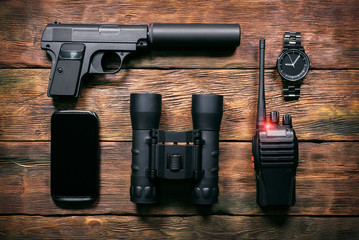Spy secret service agent equipment on the wooden table background.