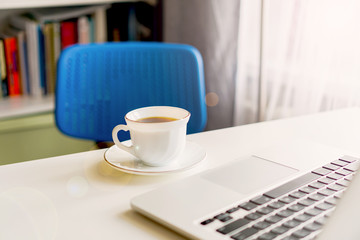 coffee mug and laptop stand on the desktop on a sunny day
