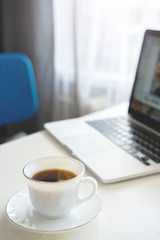 coffee mug and laptop stand on the desktop on a sunny day