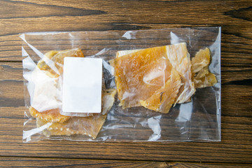 Dried cod fillet in a transparent package appetizer to beer on wooden background. Snack Fish to...