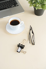 on a table on a beige background is a coffee mug, a laptop and a notebook