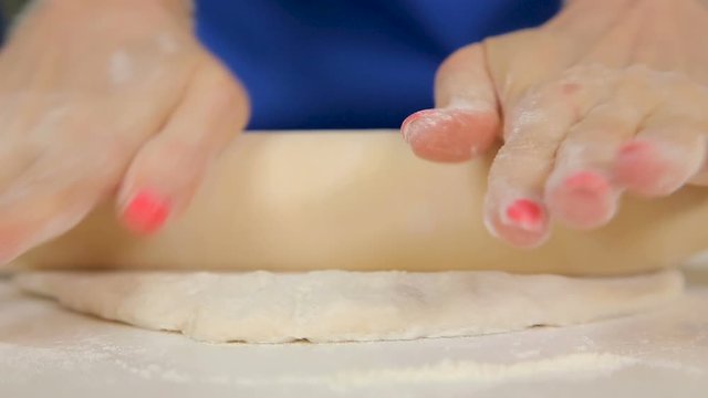 Woman kneading and rolling thin pizza dough