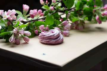 pink sweet spiral marshmallow and apple tree branch with rose flowers on wooden background
